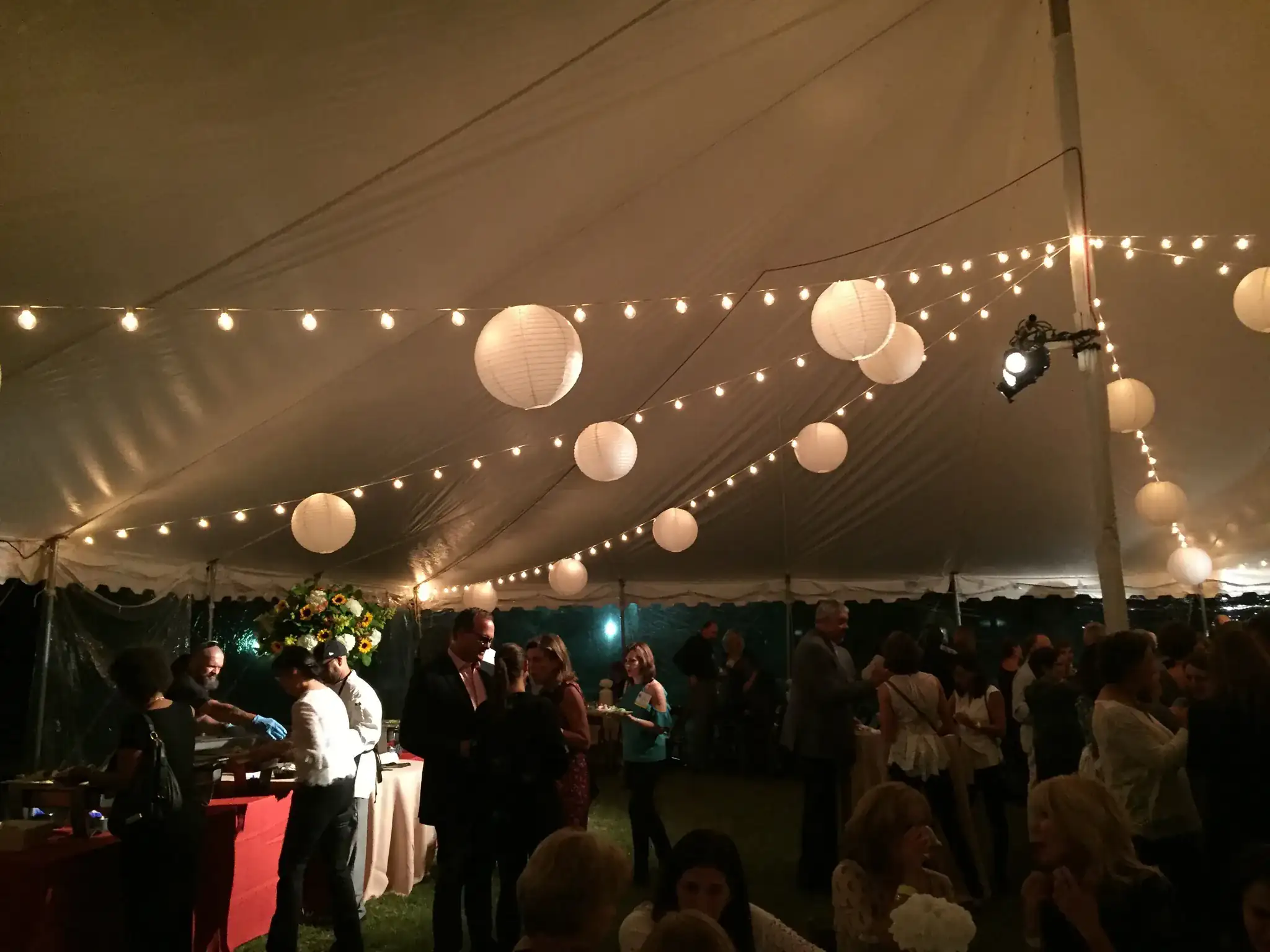 Outdoor wedding tent with string lights and floral garlands